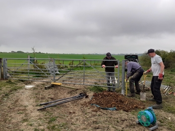 Three volunteers with spades putting in a new gate