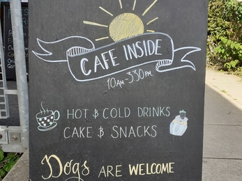 Blackboard stand with cafe opening times and details about hot and cold drinks and dog entry