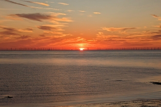 Sunset on water with wind turbines in distance