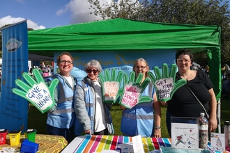 Members of the community group transition dover standing at a stall with foam hands promoting gardening