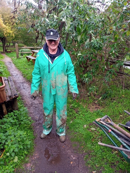 Men in bright green overalls and KWT hat covered in mud and grime