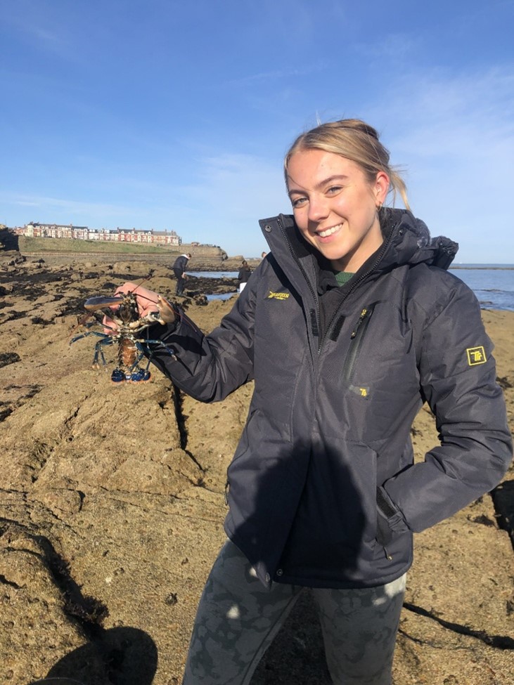 Hannah Newnham holding a lobster at the beach.