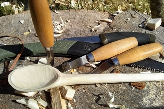 A hand carved wooden spoon and a selection of tools