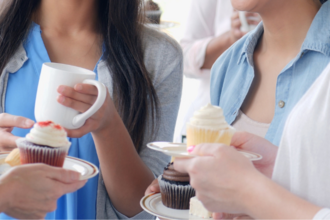 a group of people standing together with coffee and cakes