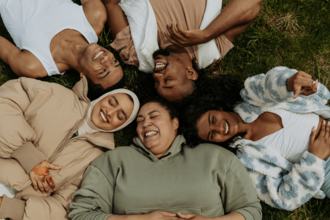 diverse group of people lying on the grass in nature laughing and smiling