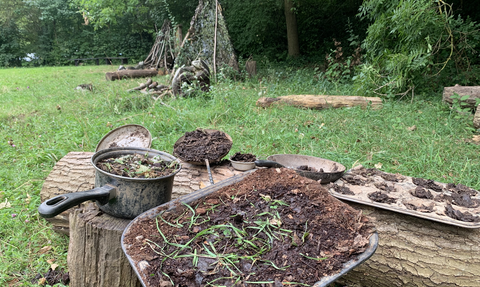 Mud cake kitchen at kent wildlife trust forest school. Kitchen items such as pans, baking trays and muffin trays are filled with mud