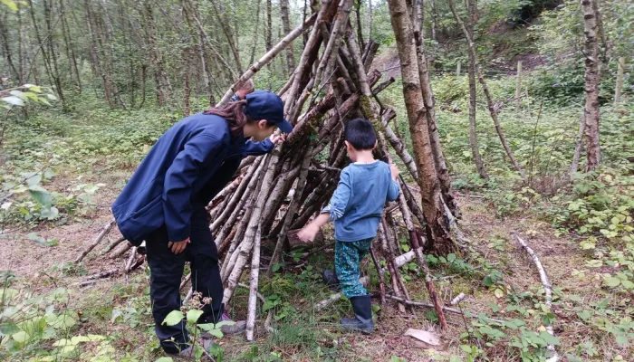 Child walks into Den as forest school leader stands by