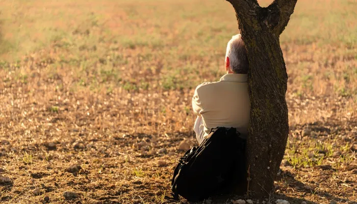 man sitting with back to tree