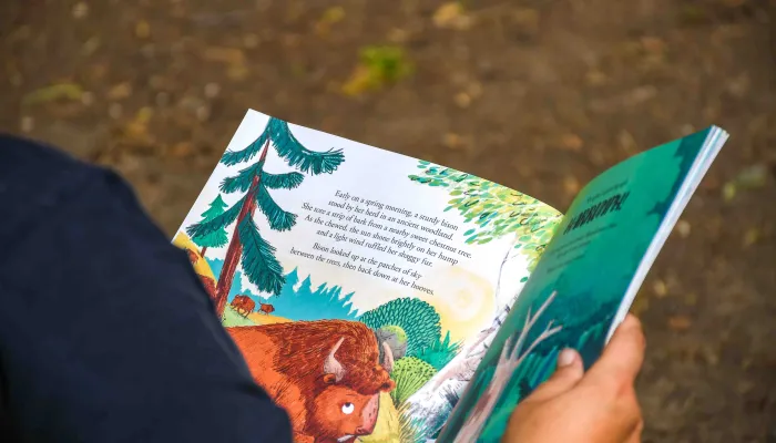 The view over a person's shoulder to a double page spread of an illustrated story book.