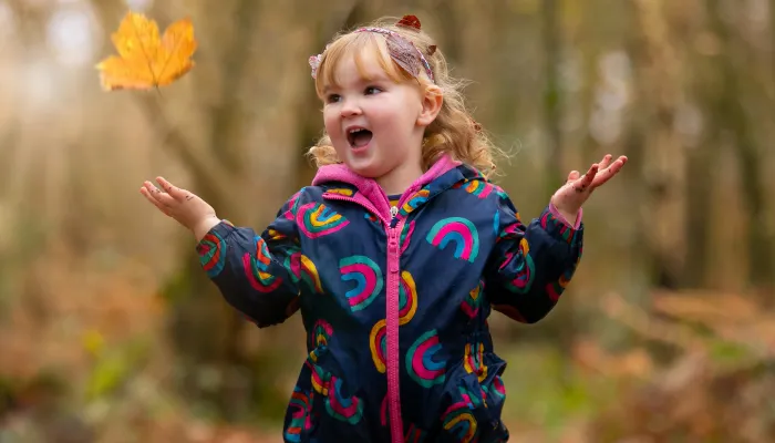 Child throwing autumn leaf in the air