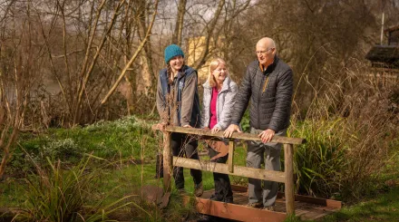 three people smiling and looking over a bridge 