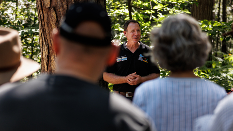 A bison ranger talks to a group of people in woodland