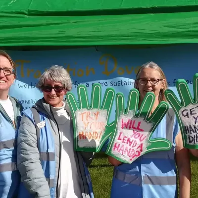 Members of the community group transition dover standing at a stall with foam hands promoting gardening