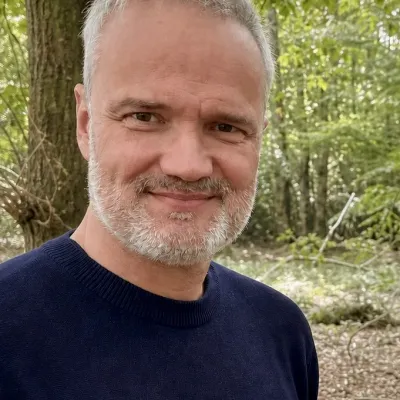 Greg Steel, Trustee, standing in a woodland.