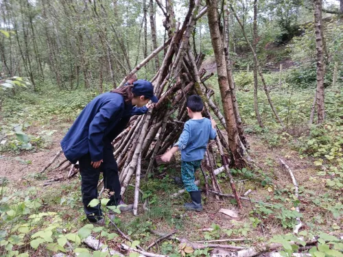 Child walks into Den as forest school leader stands by