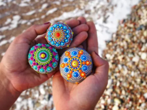 Someone holding three colourfully painted rocks in their hands.