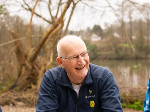 Individual person smiling outside with cup of coffee