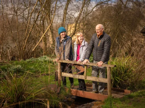 three people smiling and looking over a bridge 