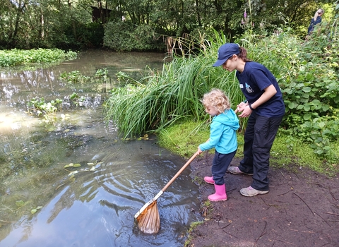 Young girl pond dipping with education tutor
